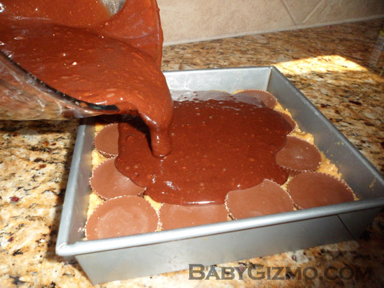 pouring brownies over peanut butter cups and cookie dough